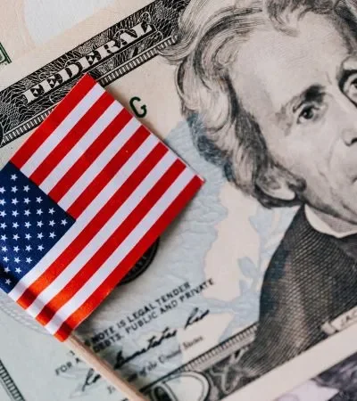 Moeda de dólar no fundo e a bandeira dos estados unidos por cima